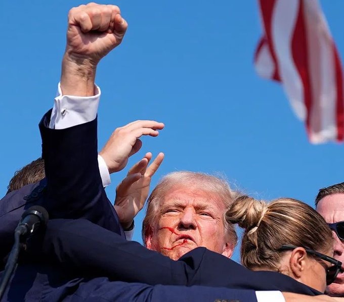 Republican presidential candidate former President Donald Trump raises his fist as he is rushed off stage after an assassination attempt during a campaign rally in Butler