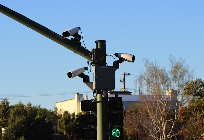 A stationary Flock-style automatic license plate reader mounted on a roadside pole